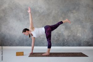 Young yogi attractive woman practicing yoga standing in twisted Half Moon exercise, Ardha Chandrasana pose. Studio shot