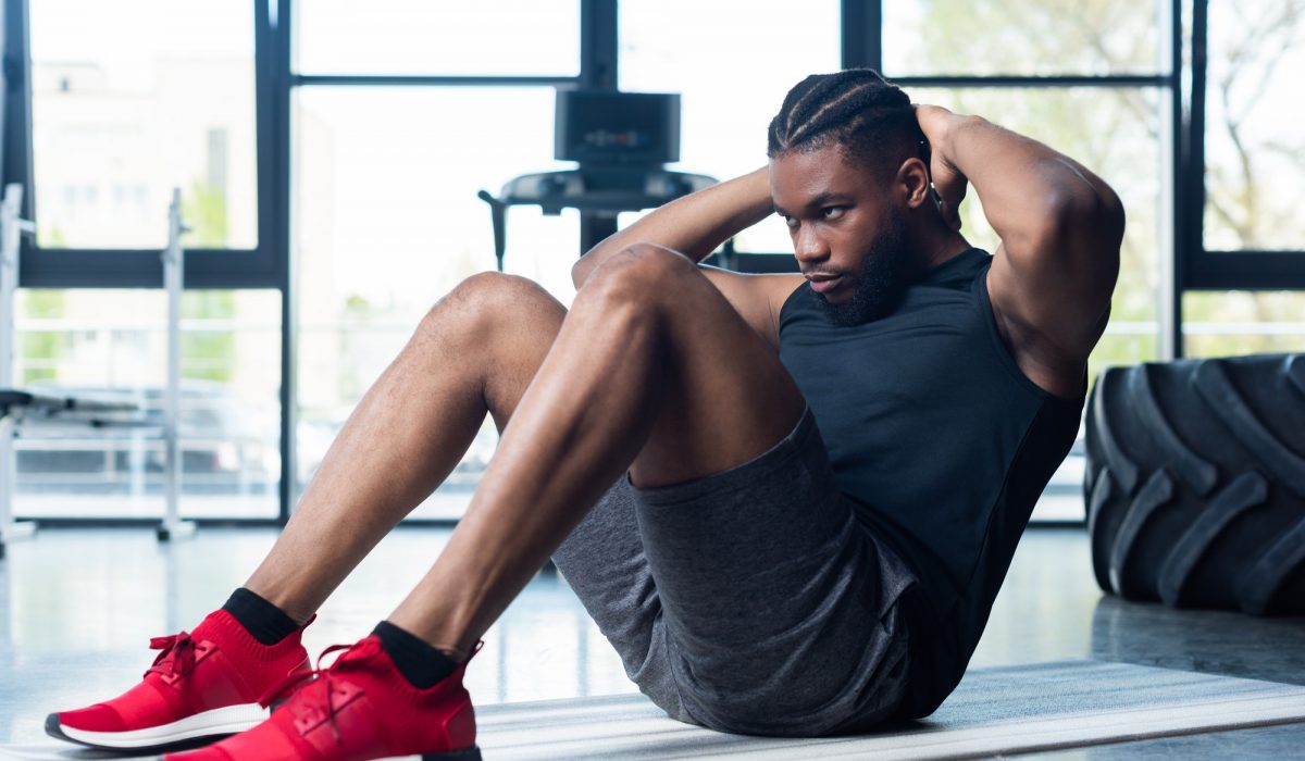 athletic young african american man doing abs and looking away in gym